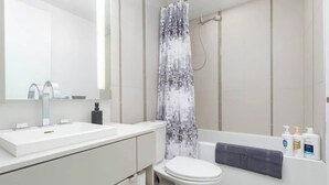 Un bany modern amb un rentapins blanc, un vàter i una cortina de dutxa.