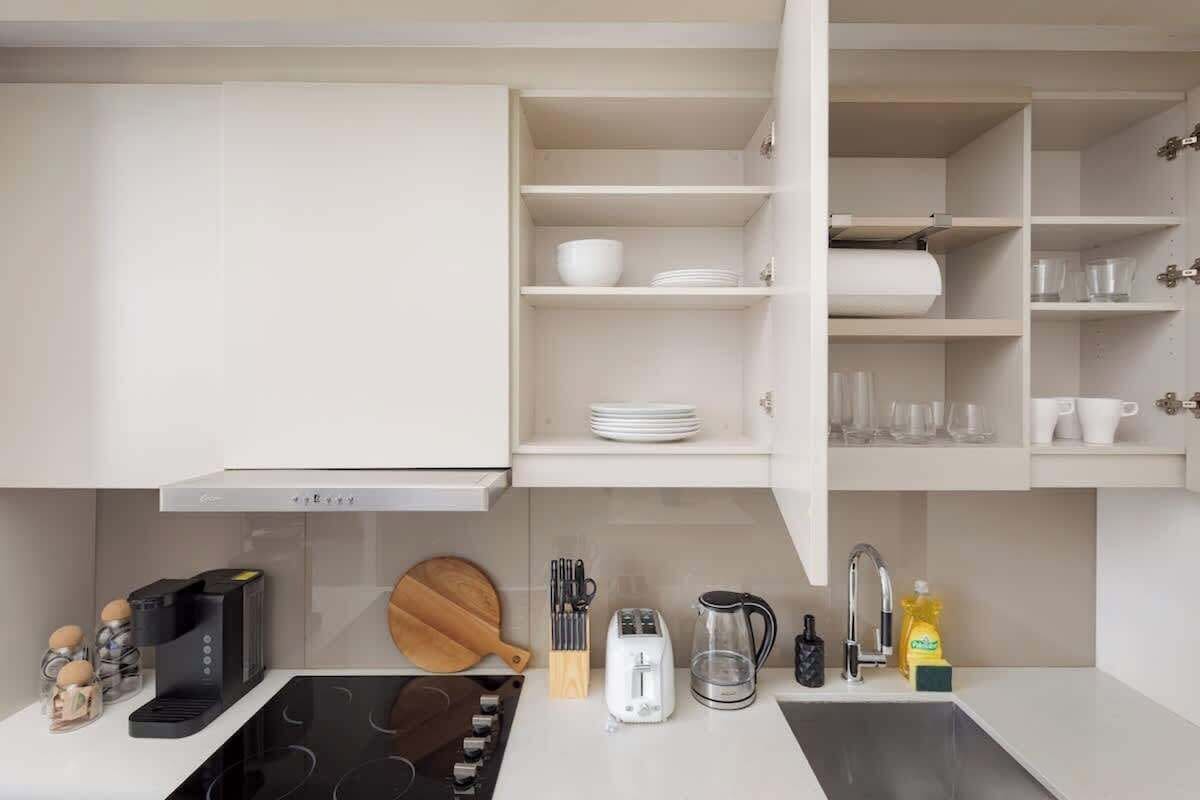 Une cuisine moderne avec des meubles blancs, une cuisinière encastrée et divers appareils de cuisine.