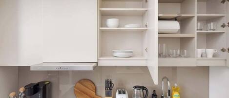 Une cuisine moderne avec des meubles blancs, une cuisinière encastrée et divers appareils de cuisine.