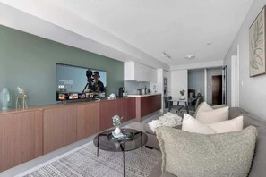 A modern living room with a sofa, a coffee table, and a television. - Modern 2BR Waterfront Retreat City Views | Parking Available (Toronto)