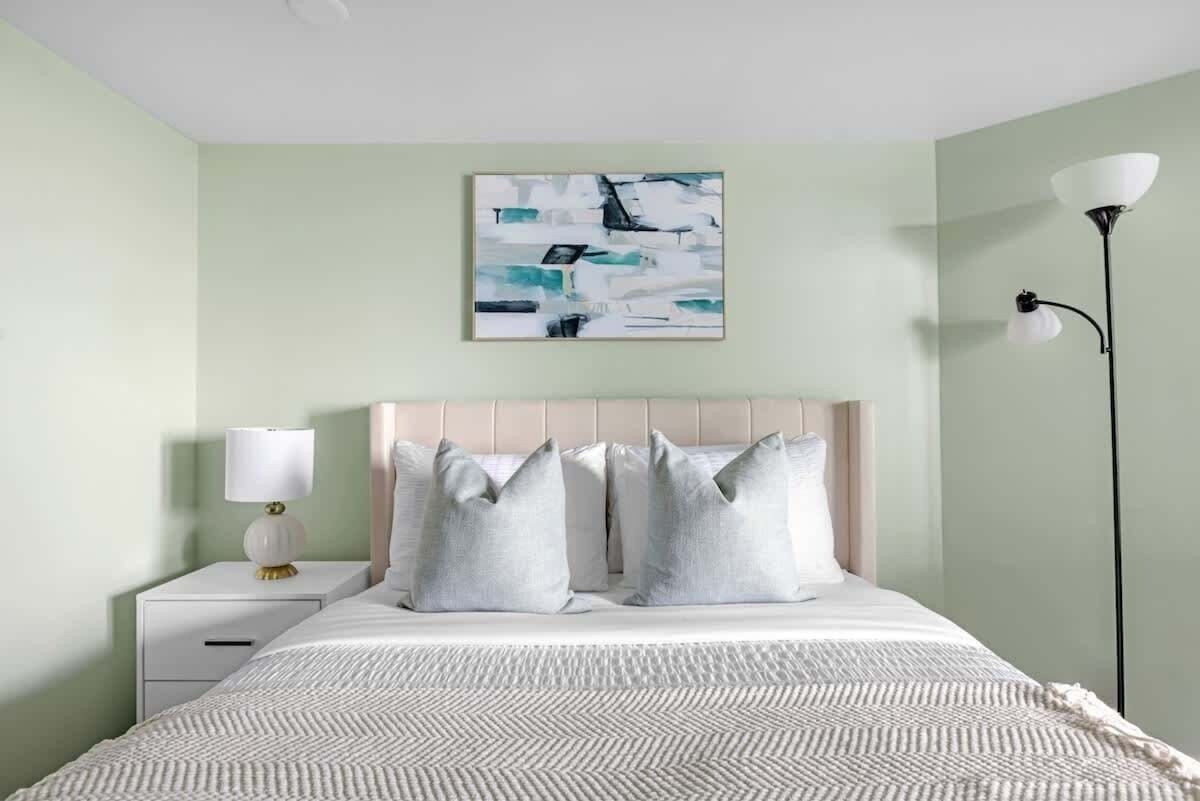A bedroom with a bed, a nightstand, a lamp, and a wall-mounted artwork.