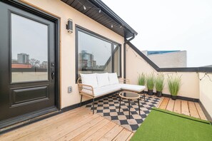 Un balcon avec un sol à carreaux, un canapé blanc et des plantes en pot.