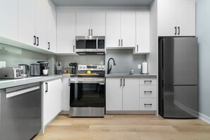 Eine moderne Küche mit Edelstahlgeräten, weißen Schränken und Holzboden.