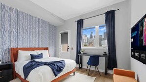 A modern hotel room with a bed, desk, chair, and a TV displaying channels. - Rare 3BR Gem, Mini Putt Terrace & CN Tower Views! (Toronto)