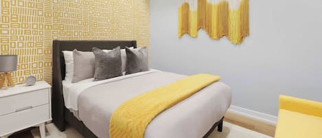 A bedroom with a bed, bedside table, lamp, and a wall hanging.