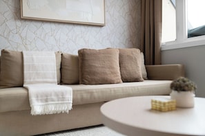 A modern living room with a sofa, pillows, a throw blanket, and a small table with a plant. - Rare 3BR Gem, Mini Putt Terrace & CN Tower Views! (Toronto)