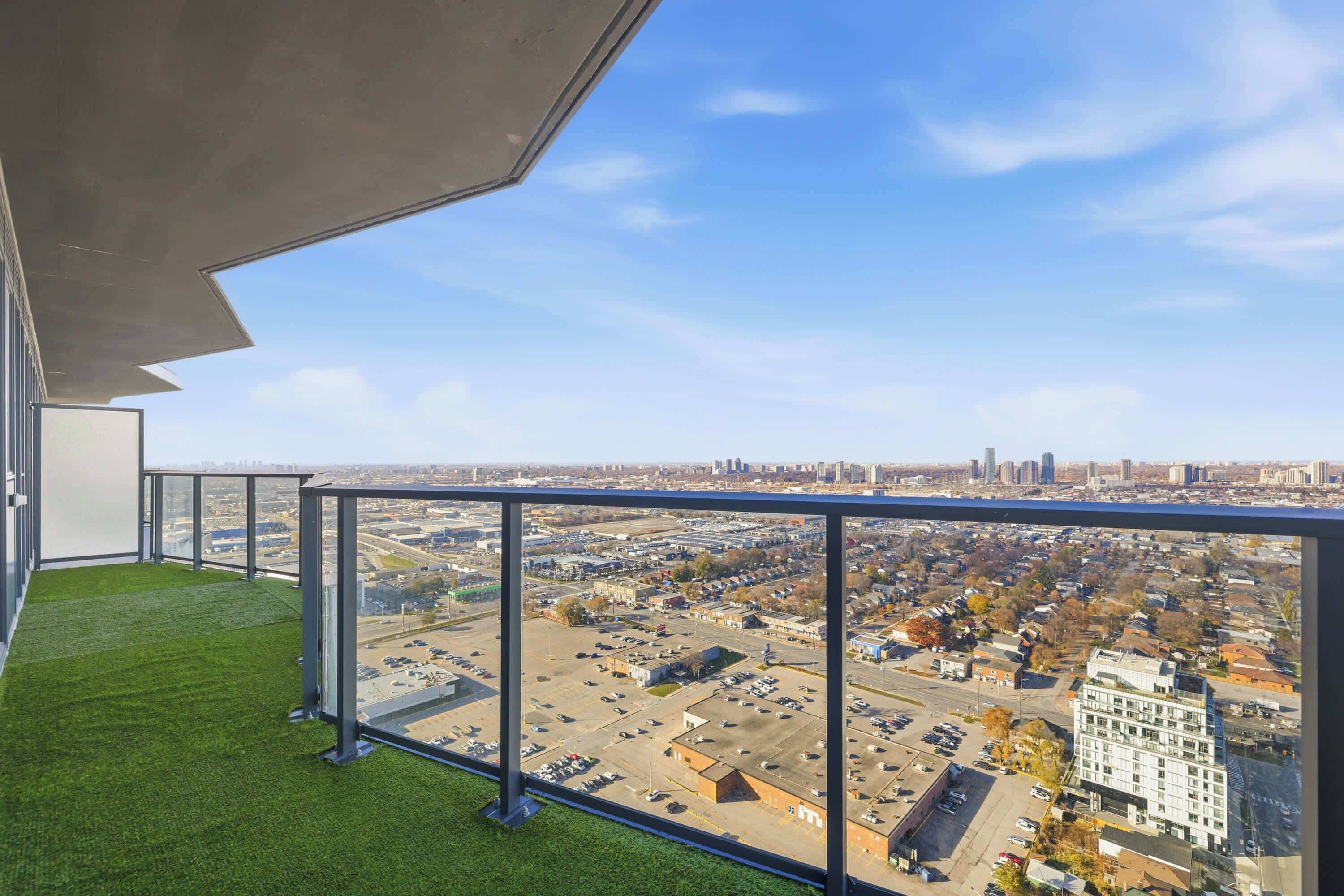 Ein Balkon mit freiem Blick auf eine Stadtlandschaft, darunter Gebäude und ein Parkplatz.