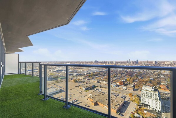 A balcony with a clear view of a cityscape, including buildings and a parking lot.