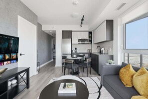 Un espai de vida modern amb zona de menjador, cuina i una finestra gran que ofereix vistes.