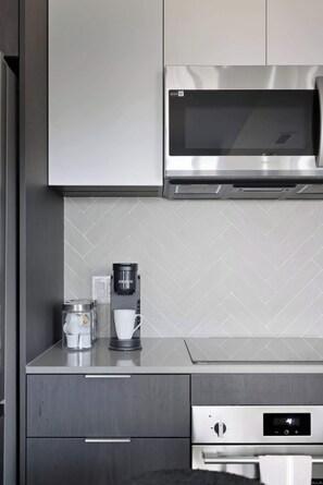A kitchen with a microwave, coffee maker, and a kettle on the counter.
