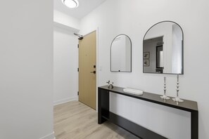 Un baño moderno con un mueble de tocador oscuro, un lavabo blanco y dos espejos fijos en la pared.