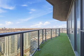 Un balcón con barandilla de vidrio que da a una vista panorámica de la ciudad.