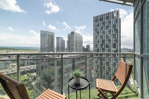 A balcony with a view of high-rise buildings, a small table with a plant, and two wooden chairs. - CityPlace 2BR Escape | Balcony & 2 Bathrooms (Toronto)