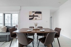A modern dining area with a wooden table, six chairs, and a minimalist abstract painting on the wall.