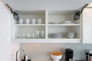 A kitchen with white cabinets, a coffee maker, and a sink.