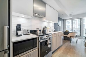 A modern kitchen with a built-in oven, a coffee maker, and a stove. - Modern 1BR, Designer Condo, Sleeps 4 | Parking Available (Toronto)