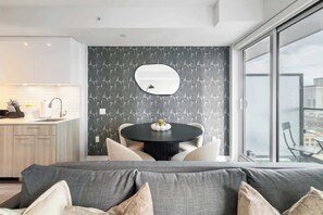 A modern interior with a dining area, a large window, and a sofa. - Modern 1BR, Designer Condo, Sleeps 4 | Parking Available (Toronto)