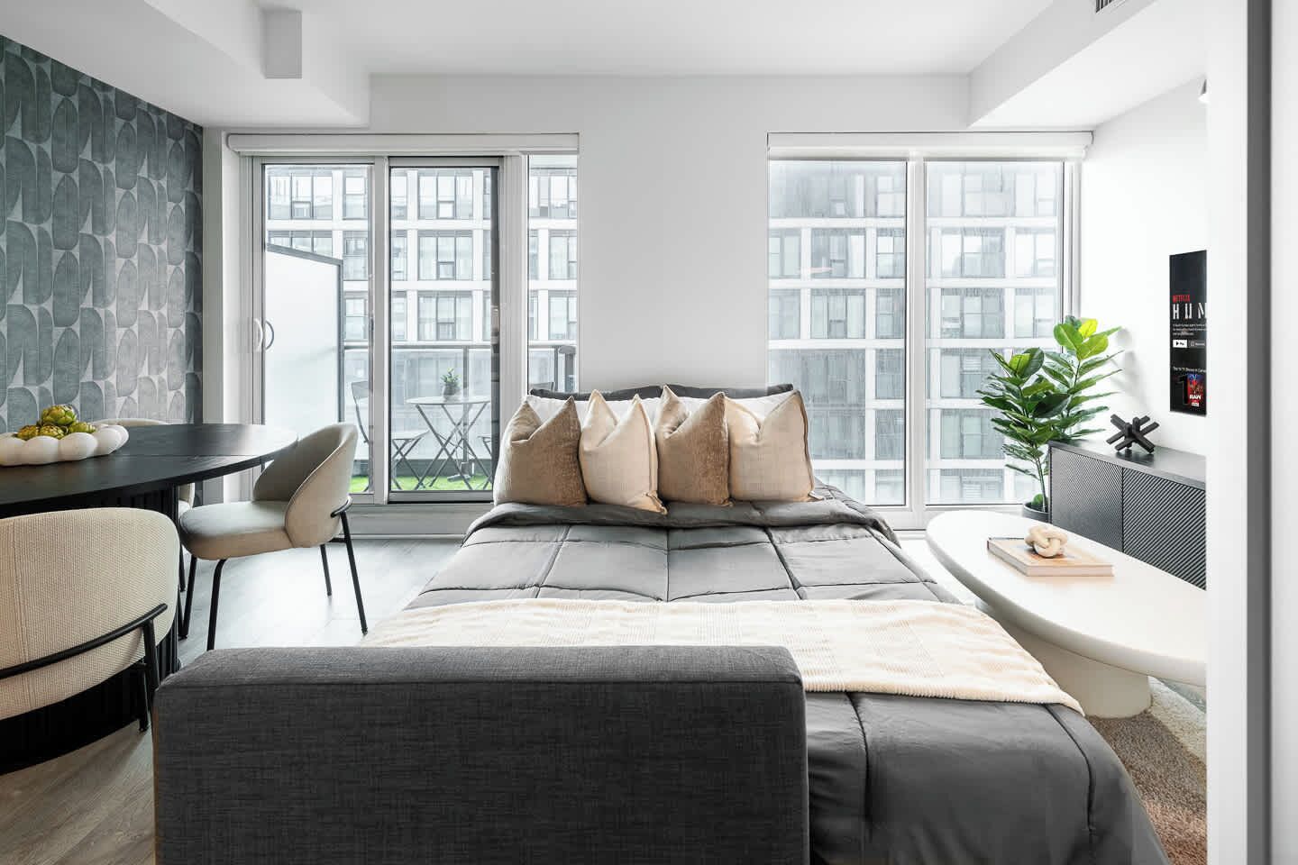 A modern bedroom with a bed, a desk, and a large window.