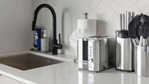 A modern kitchen with a stainless steel sink, a toaster, and a knife block.