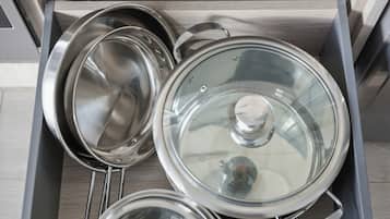 A drawer with stainless steel kitchenware including pots and pans.