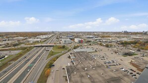 A multi-level parking structure with several lanes of traffic and a large industrial area in the background.