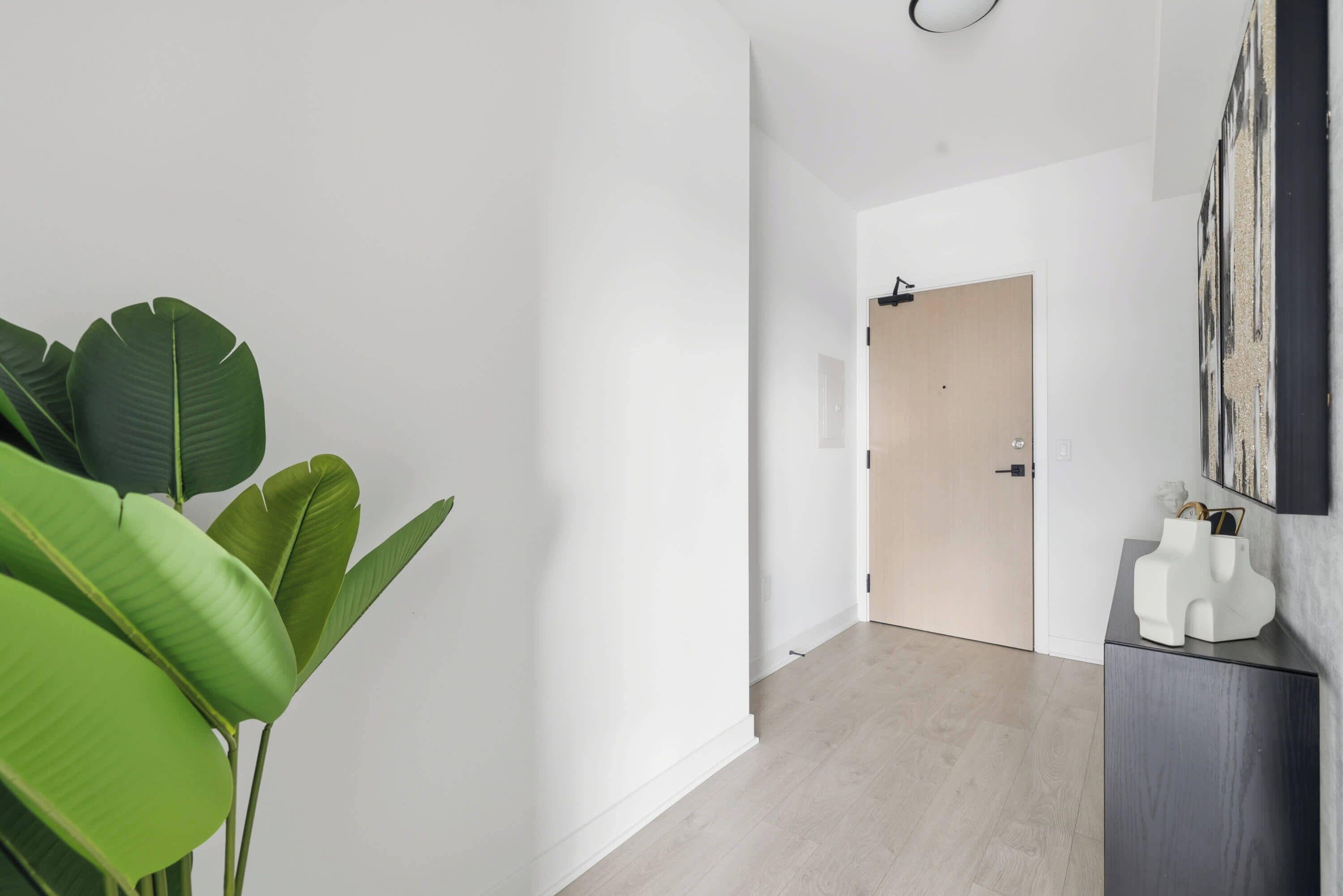 A hallway with a wooden floor, a door, and a wall-mounted artwork.