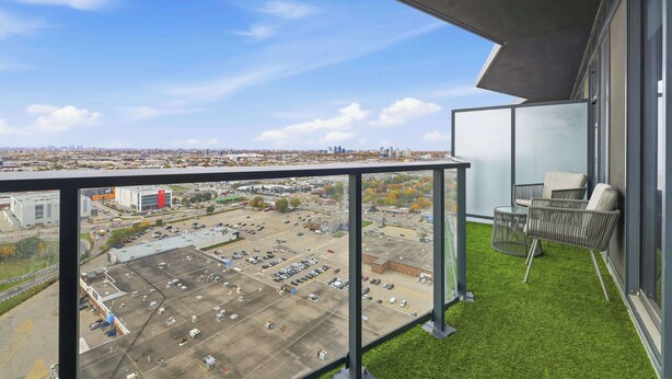 A balcony with a view of a parking lot and cityscape.