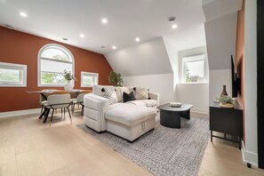 A modern living room with a sectional sofa, a coffee table, and a TV on a stand. - Free Parking! Dual King Suite | West End Gem  | Parking Available (Toronto)