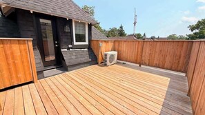 Eine Holzterrasse mit einem kleinen Gebäude, einem Fenster und einer Klimaanlage.