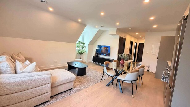 Ein modernes Wohnzimmer mit einer Couch, einem Glastisch und einem an der Wand befestigten Fernseher.