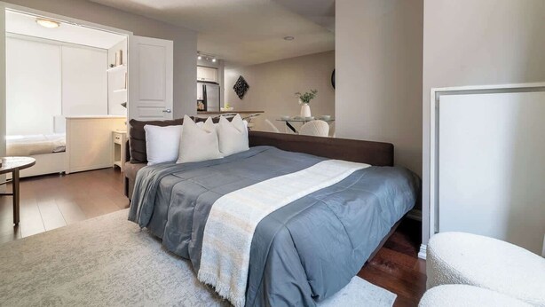 Quarto com cama, mesa de cabeceira e pequena área de estudo.