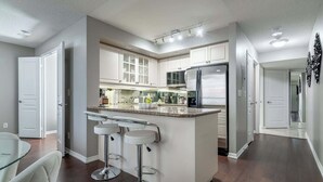 Uma cozinha moderna com uma ilha central, banquetas e uma geladeira de aço inoxidável.