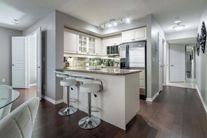 Eine moderne Küche mit einer zentralen Kochinsel, Barhocker und einem Edelstahlkühlschrank.