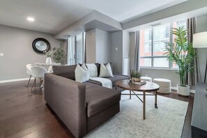 Ein modernes Wohnzimmer mit einer Couch, einem Couchtisch und einem Essbereich mit einem Sessel und Tisch.