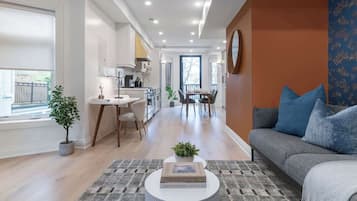 A modern living room with a sofa, coffee table, and a dining area with chairs and a table.