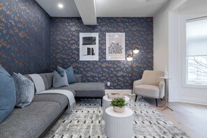 A modern living room with a grey sofa, a round coffee table with a plant, and a white armchair.