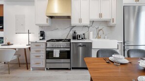 Una cocina moderna con muebles blancos, electrodomésticos de acero inoxidable y salpicadero de mármol.