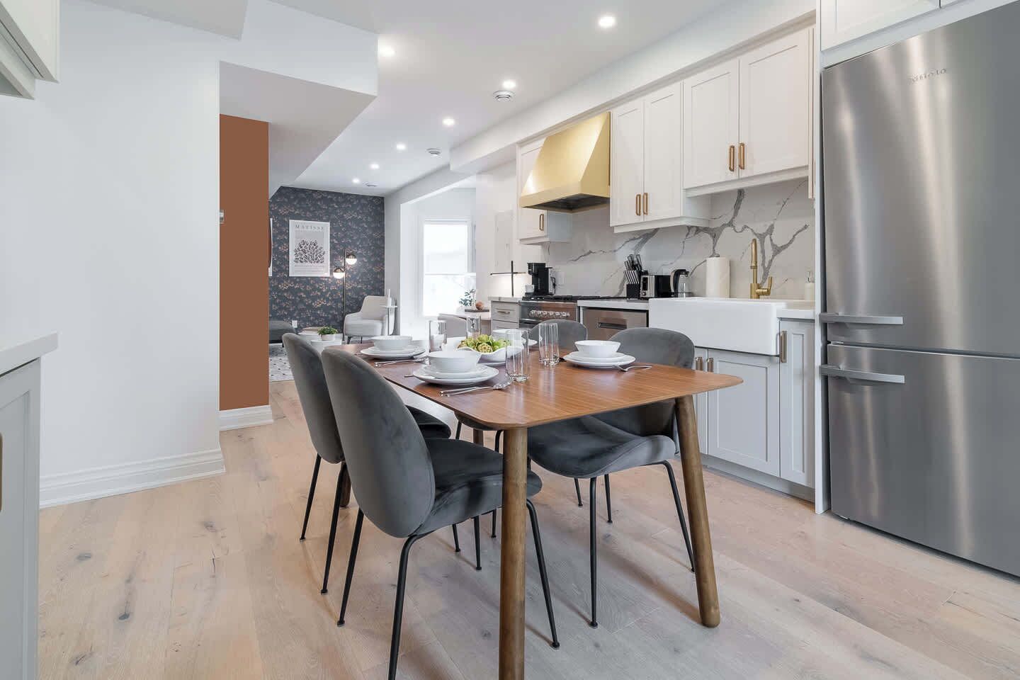 A modern kitchen with a dining area, stainless steel appliances, and a marble backsplash.