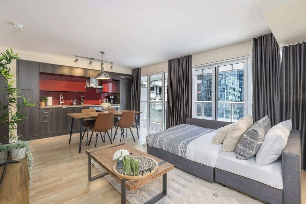 Un appartement moderne comprenant un coin repas, une kitchenette et un grand lit agrémenté de plusieurs oreillers.