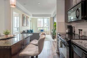 Eine moderne Küche mit integriertem Mikrowellenherd, Herd und Backofen. Es gibt eine Sitzecke mit einer Couch und Sesseln.