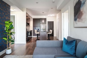 Ein modernes Wohnzimmer mit grauem Sofa, einem Couchtisch und einer großen Küstertopf-Pflanze.