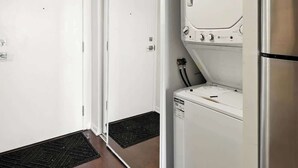 A modern kitchen with a built-in refrigerator, a washing machine, and a shower area with a glass door. - Downtown Financial District Gem Sleeps 5 55"TV (Toronto)