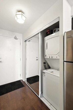 Eine moderne Küche mit Einbaukühlschrank, Waschmaschine und Duschbereich mit Glastür.