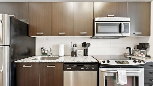 A modern kitchen with stainless steel appliances, a dishwasher, and a microwave. - Downtown Financial District Gem Sleeps 5 55"TV (Toronto)