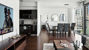 A modern kitchen with dark cabinetry, a microwave, and a dining area with a table and chairs. - Downtown Financial District Gem Sleeps 5 55"TV (Toronto)