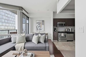 Ein modernes Wohnzimmer mit einem grauen Sofa, einem Couchtisch und Blick auf die Küche.