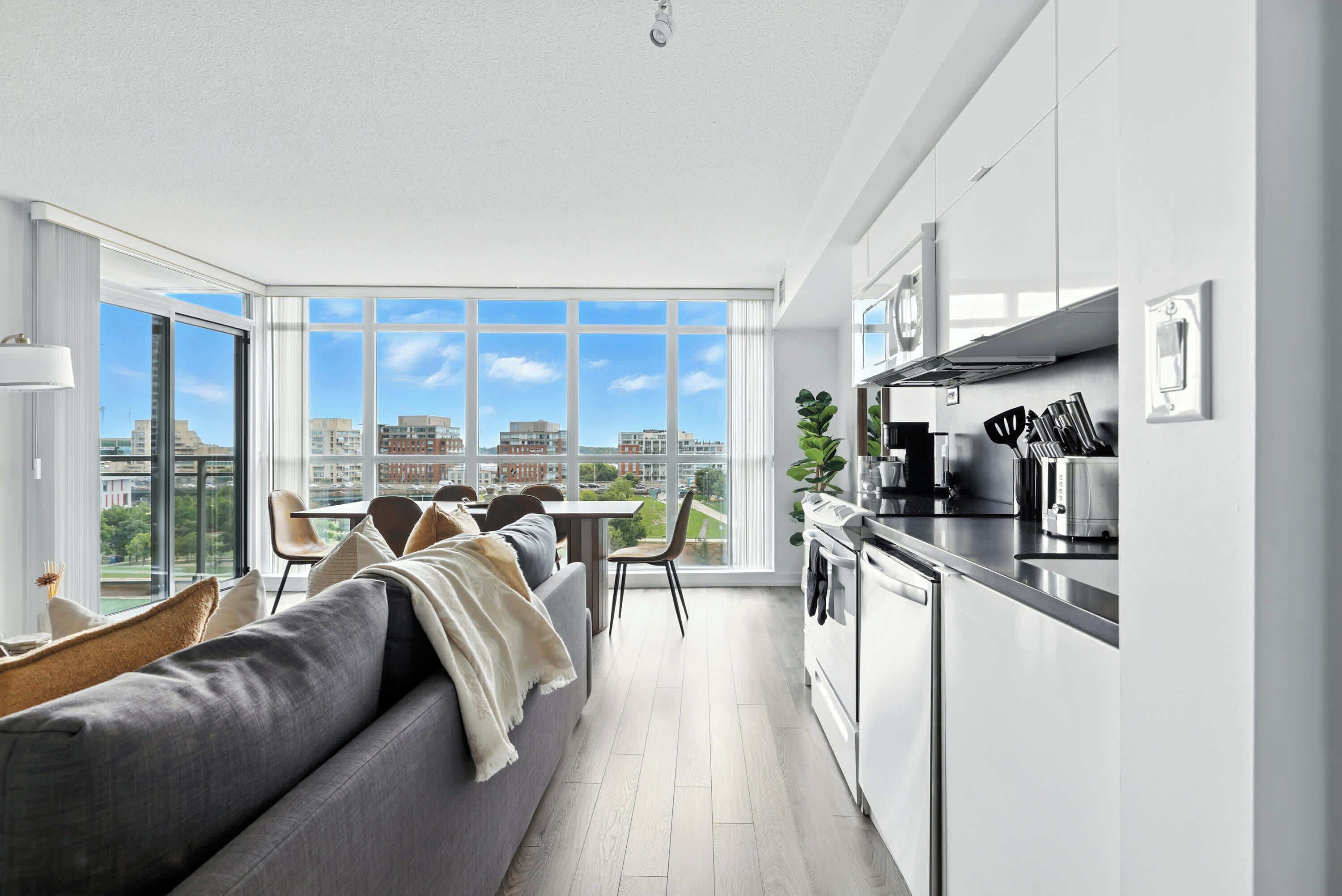 A modern kitchen with a dining area, large windows, and a view of the city.