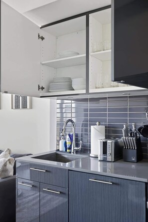 A modern kitchen with a built-in dishwasher, a stainless steel sink, and a toaster. - Urban 2BR Suite near Yonge-Dundas | Private Balcony | Parking Available (Toronto)