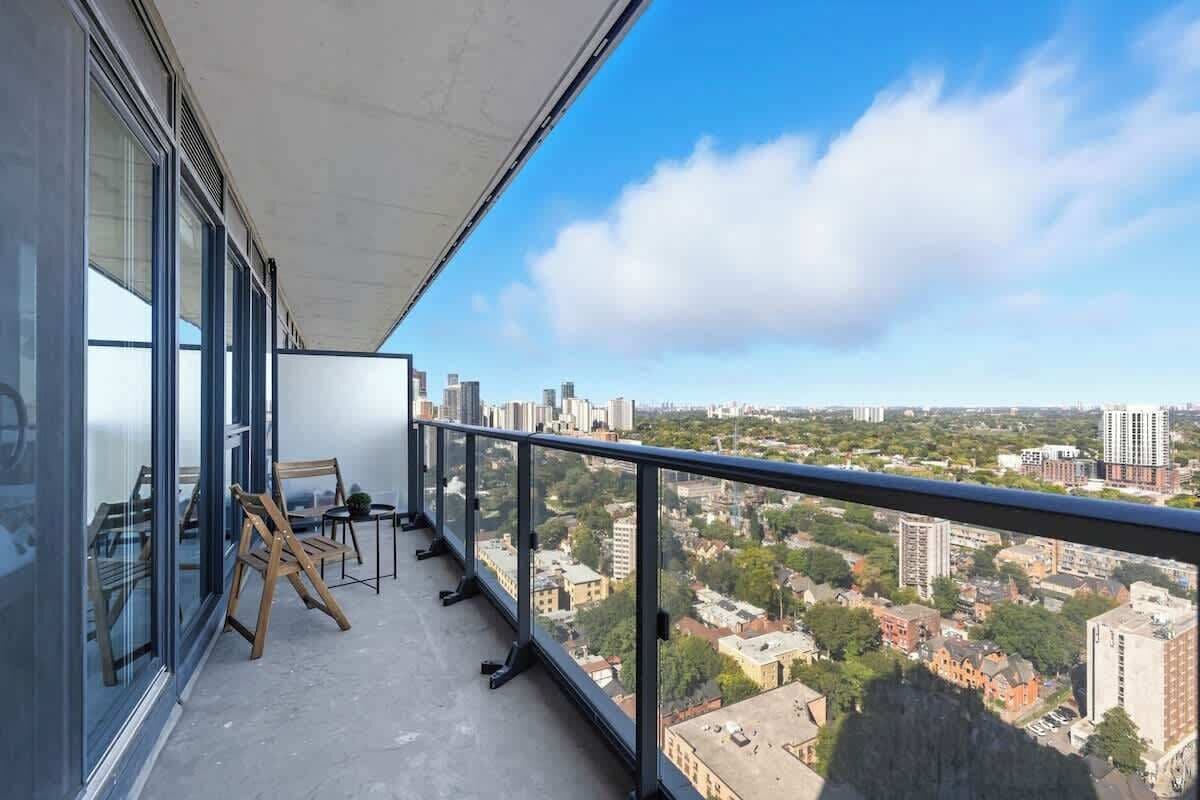 A balcony with a city view, a wooden chair, and a small table.