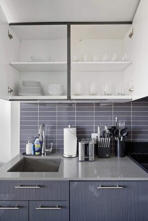 Een moderne keuken met een ingebouwde vaatwasser, een koffiezetapparaat en een set messen op het aanrecht.